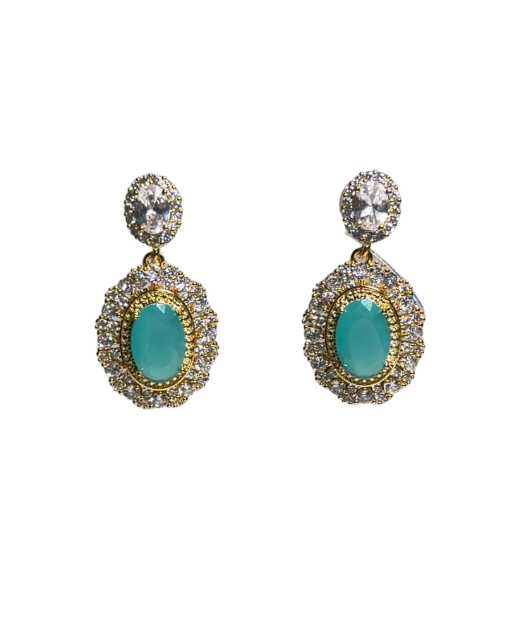 A pair of gold drop earrings featuring oval turquoise-colored center stones surrounded by small clear crystals, with a round clear crystal stud above, set against a plain white background.